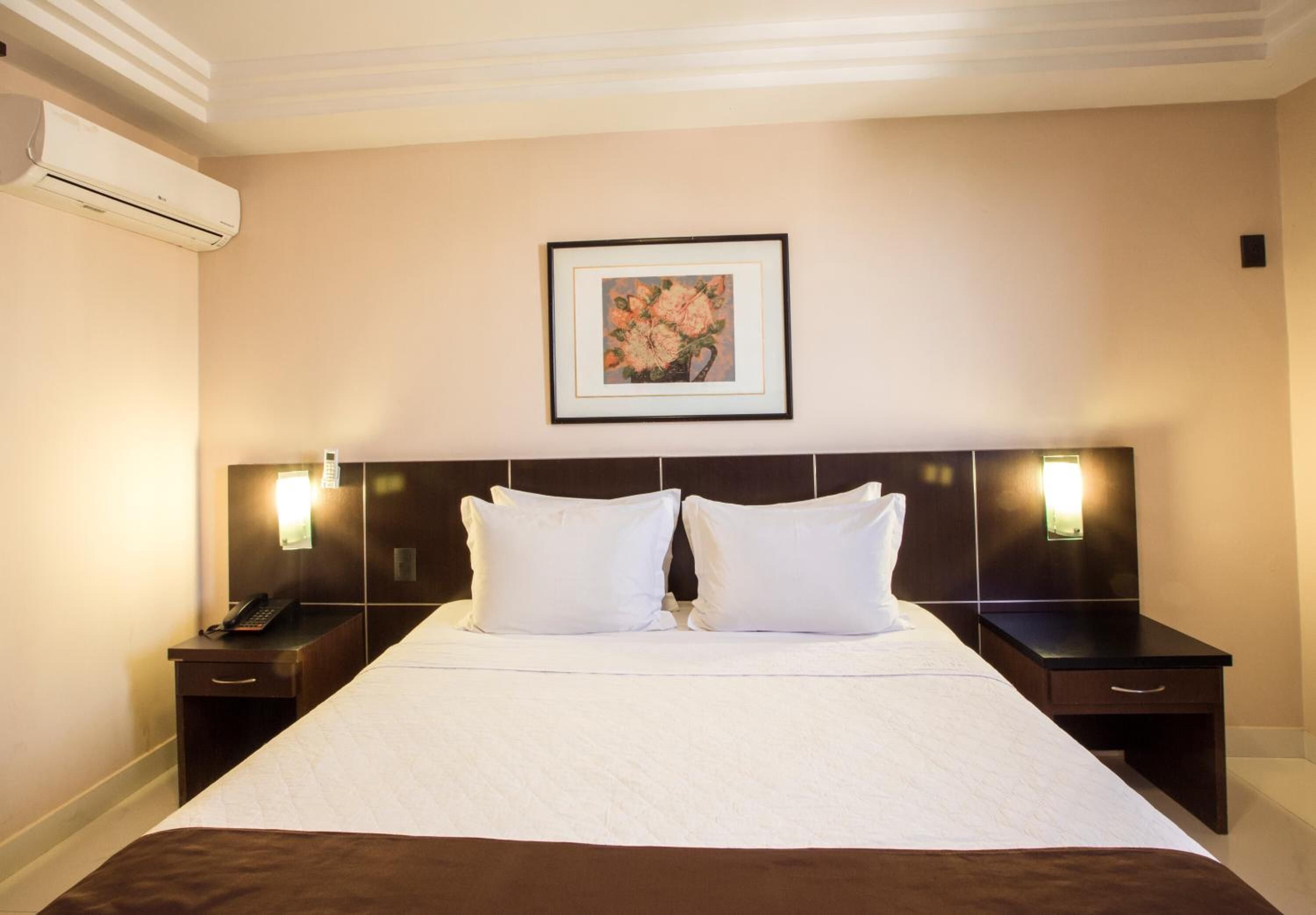 Habitación de hotel con una cama grande, dos mesitas de noche y un climatizador de aire.