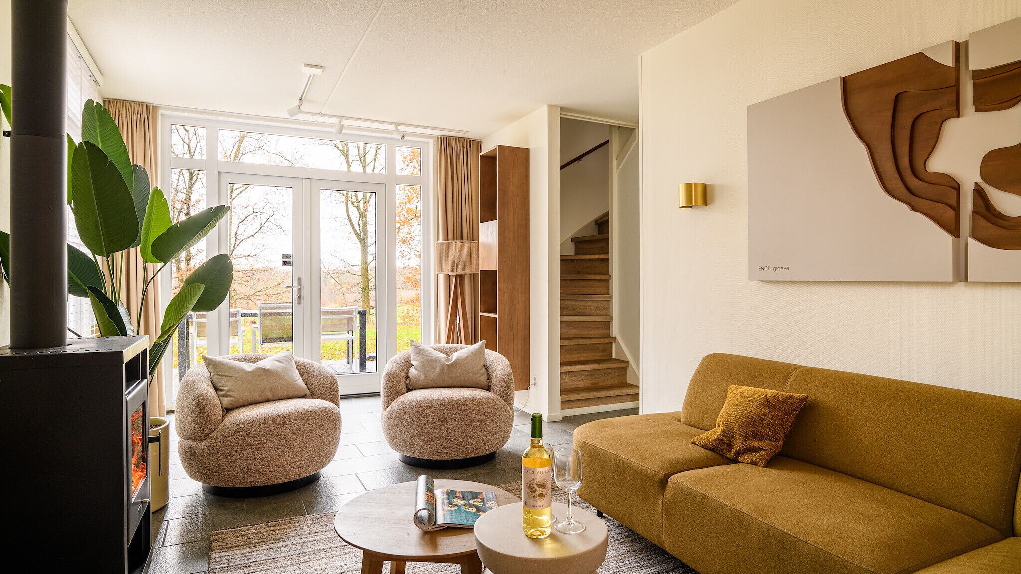 A modern living room with a sofa, two armchairs, a coffee table, and a fireplace.