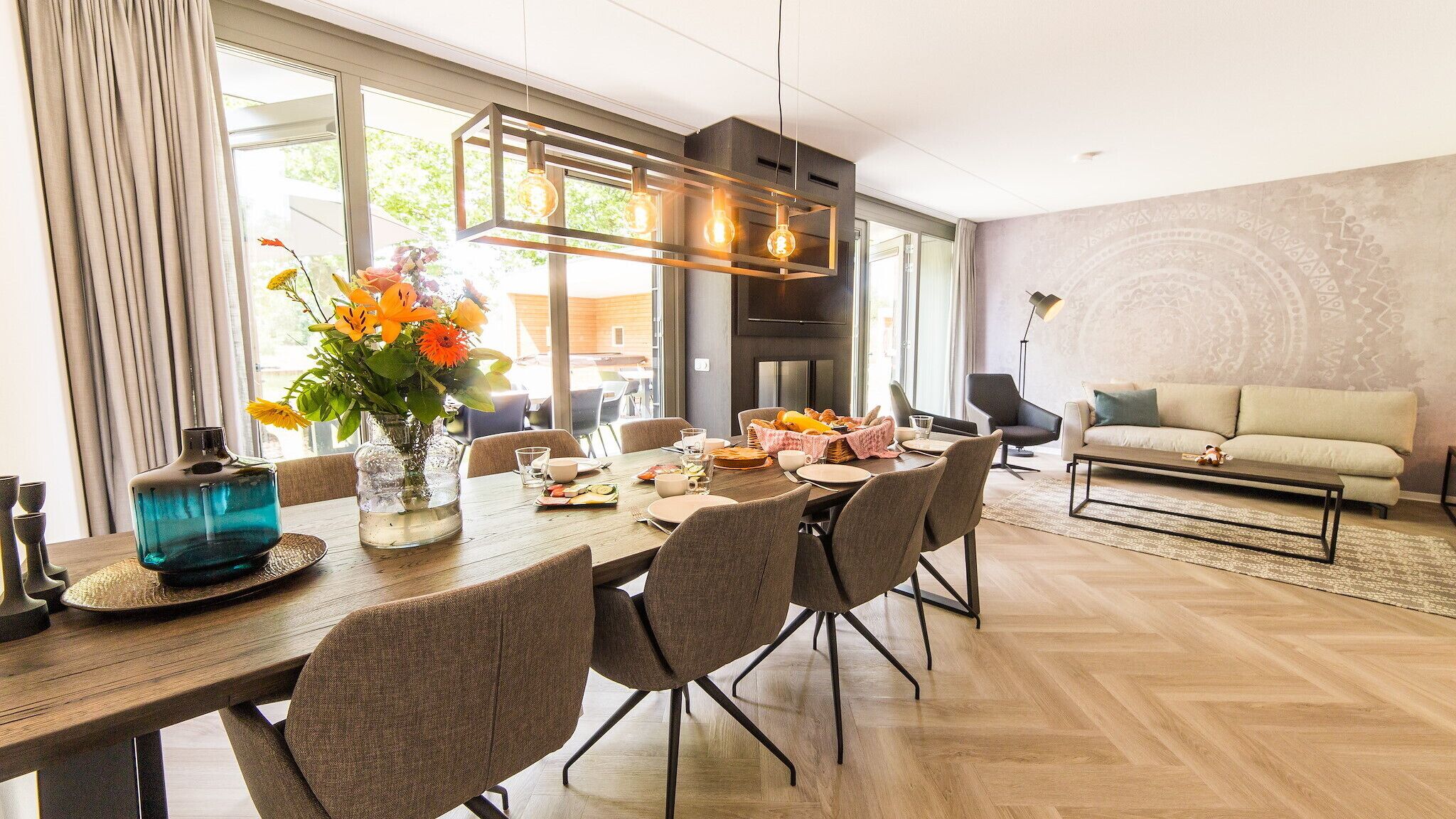 Un espace repas moderne avec une table en bois, des chaises et un vase de fleurs.