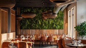 A restaurant with wooden walls, green plants, and brown furniture. - Dormio Resort Maastricht (Maastricht)