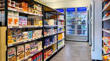 Een gang in een supermarkt met schappen vol diverse etenswaren en een koelvitrine op de achtergrond.