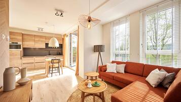 A modern living room with a sofa, coffee table, and a dining area with a table and chairs.