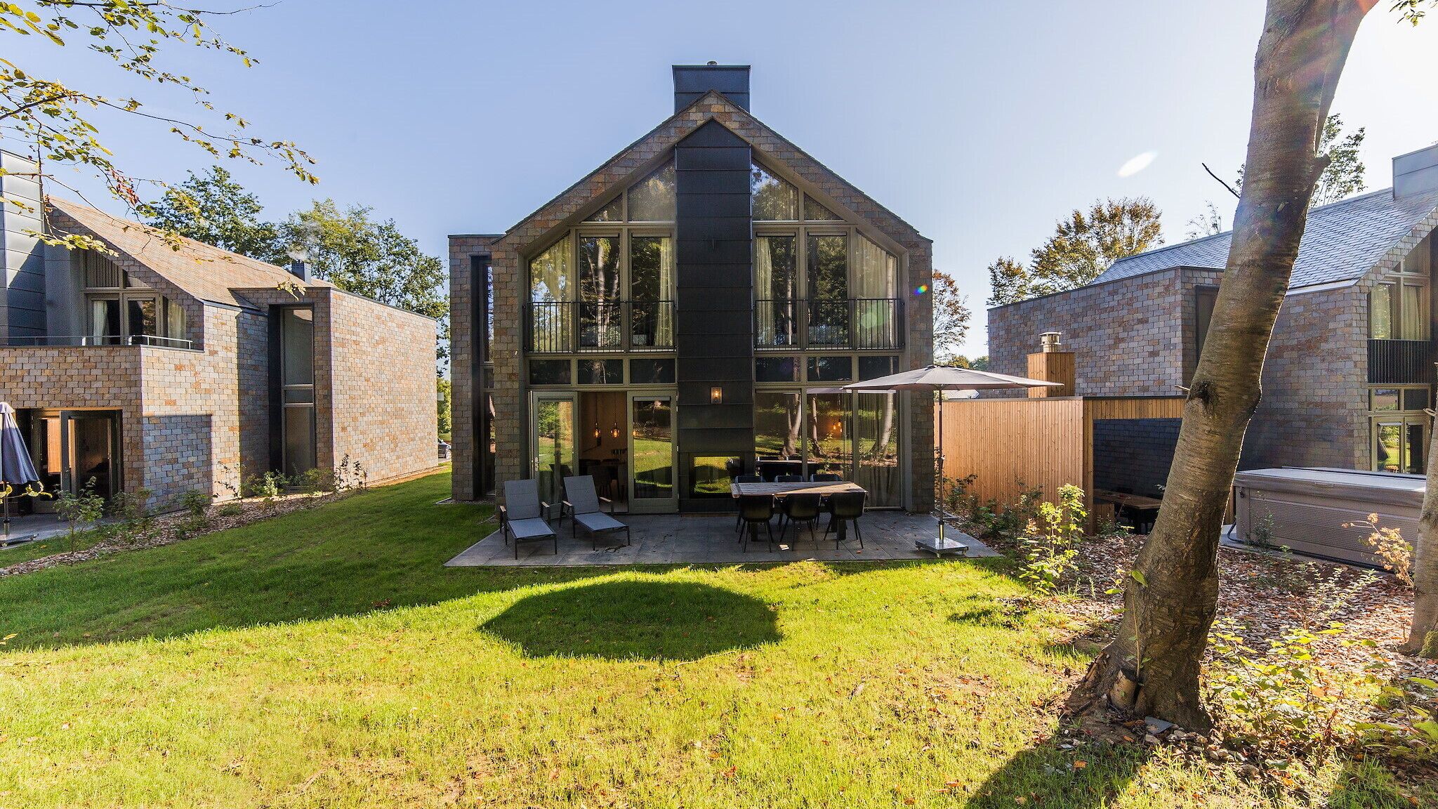 A modern house with a large patio, a dining area, and a fireplace.