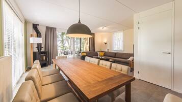 Ein modernes Wohnzimmer mit einem Holzespeisetisch, beigen Sofas und einem großen Fenster, das für natürliches Licht sorgt.