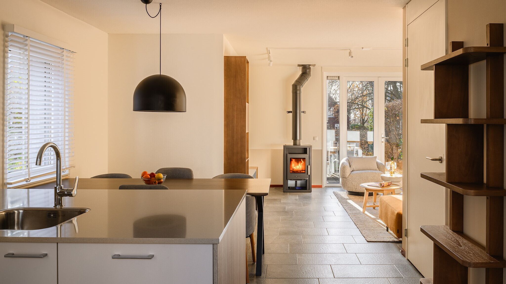 A modern kitchen with a central island, a built-in stove, and a dining area with a view of the outdoors.