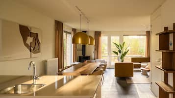 A modern kitchen with a central island, a dining area with a long table, and a seating arrangement.