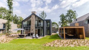 A modern two-story house with a stone facade, large windows, and a patio area with outdoor furniture. - Dormio Resort Maastricht (Maastricht)