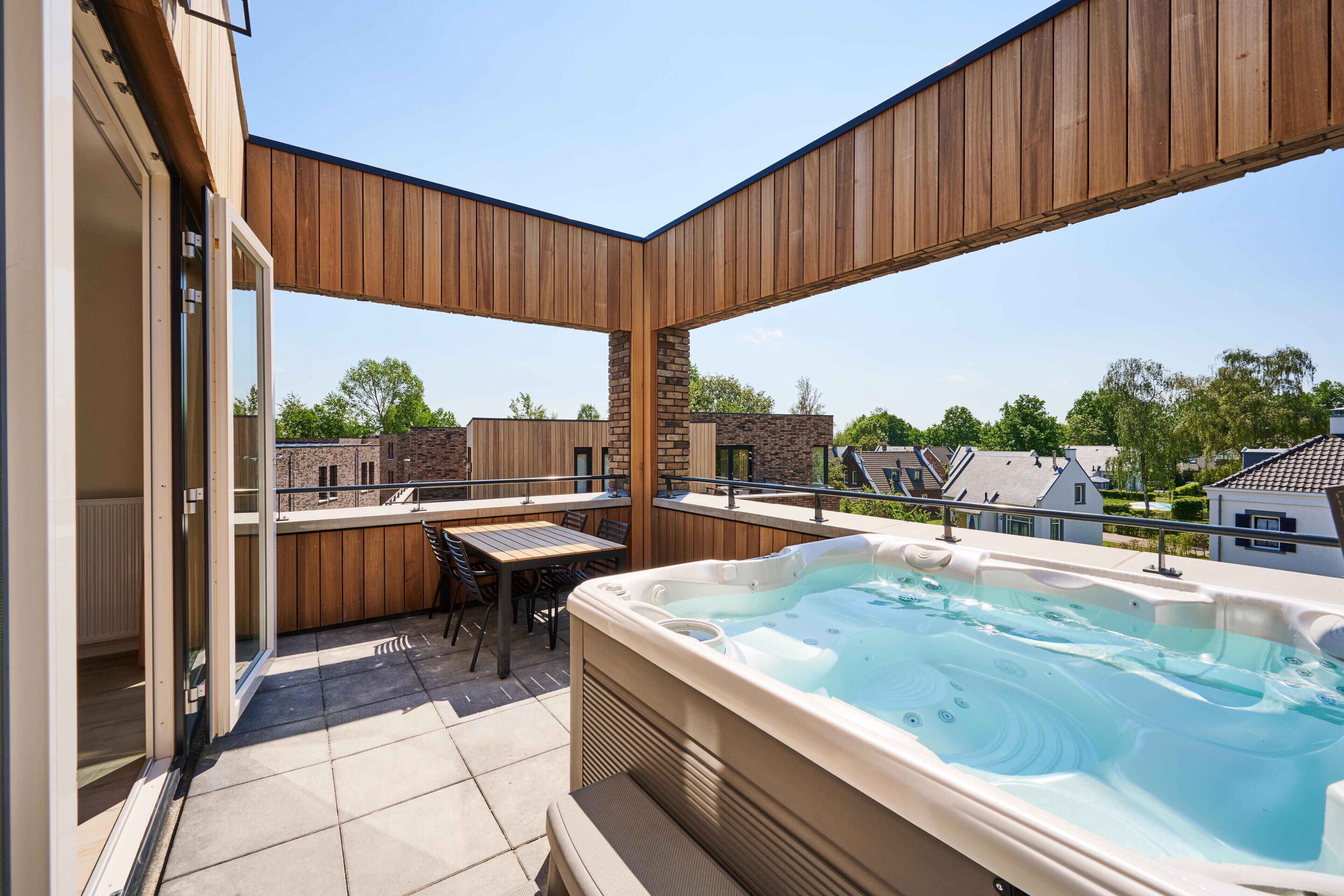 A modern outdoor patio with a hot tub, wooden pergola, and a dining area.