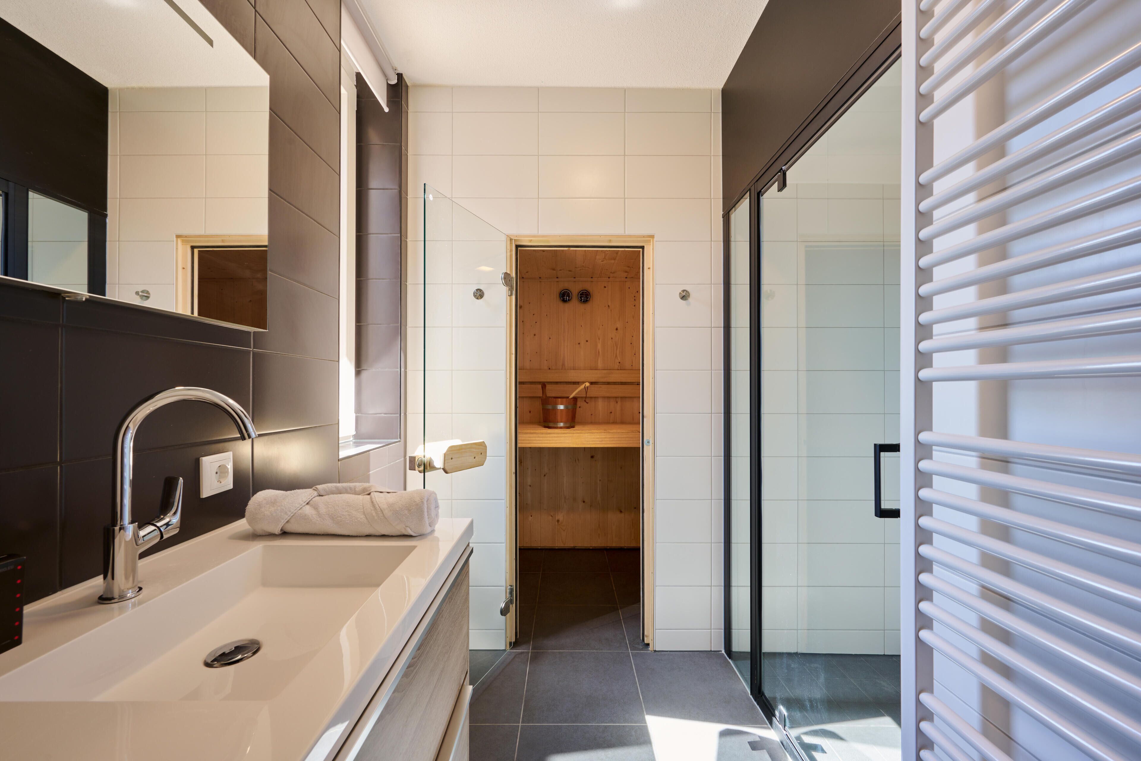 Une salle de bain moderne avec un grand miroir, une baignoire, une douche et un sauna.