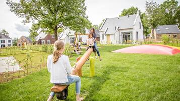 A residential area with a playground, including a seesaw and a swing set.