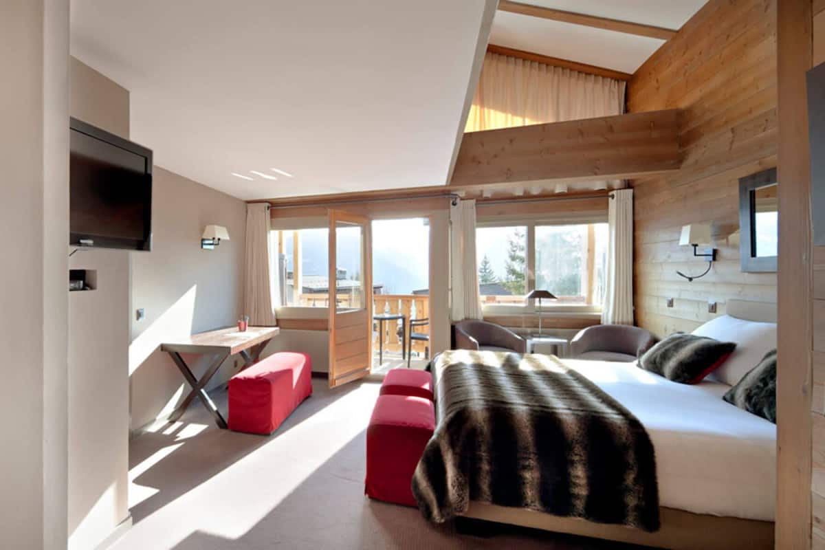 A modern bedroom with a bed, a desk, and a staircase.