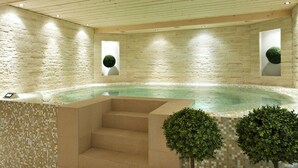 A hot tub area with a stone wall, tiled steps, and two small trees.