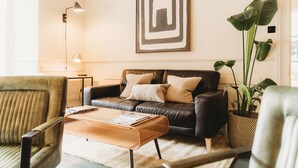 A modern living room with a leather sofa, a coffee table, and a large plant.