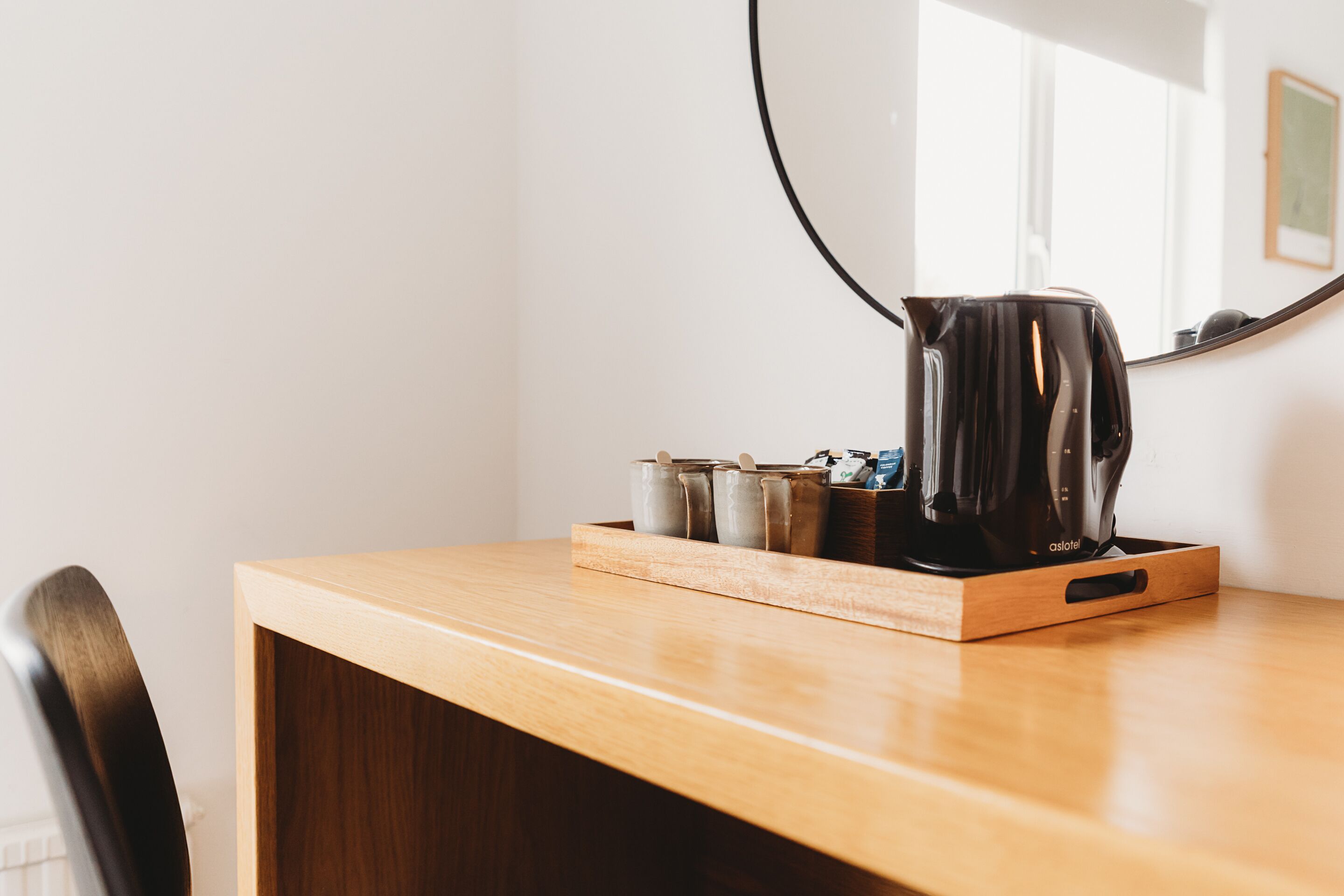 Une table en bois avec une machine à café, des bocaux et une bouilloire.