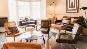 A modern living room with a sofa, armchairs, a coffee table, and a floor lamp.