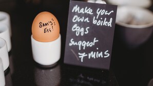 A single egg labeled "Sam's Egg" on a white stand, with a sign suggesting to make your own boiled eggs, accompanied by a suggestion of 7 minutes.