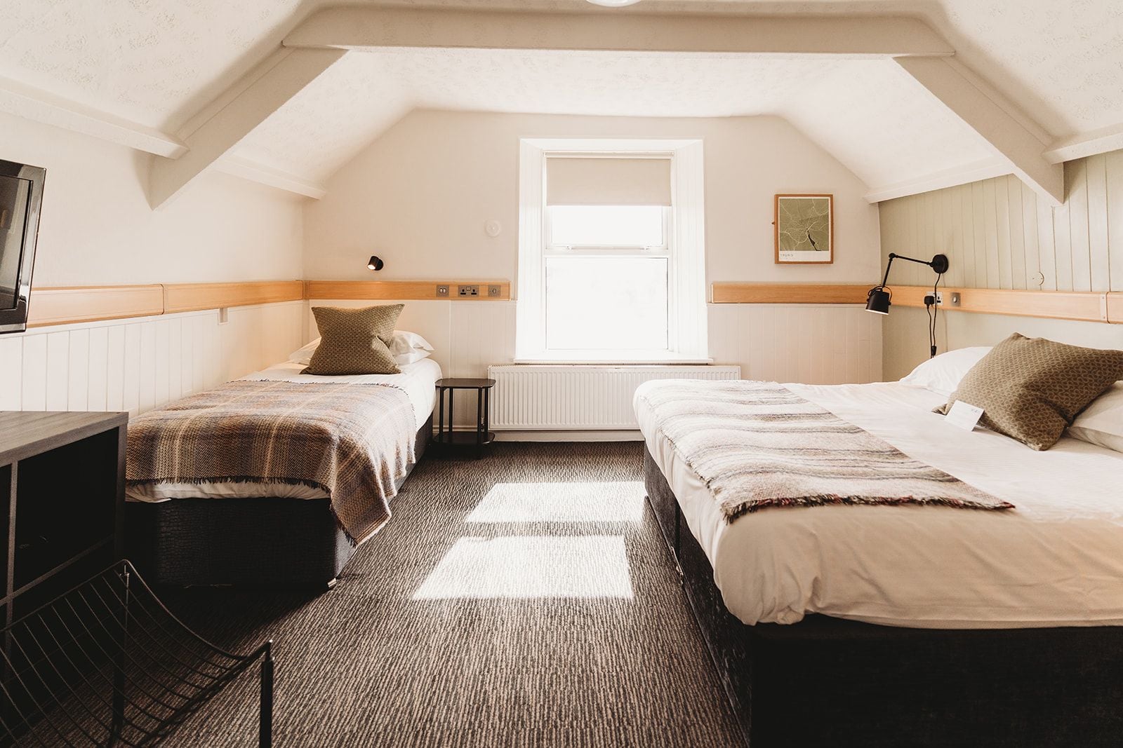 A room with two beds, a desk, and a radiator.