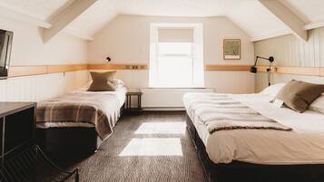 A room with two beds, a desk, and a radiator.