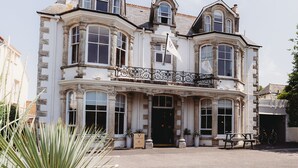 A historic building with a prominent entrance, large windows, and a balcony with ornate ironwork.