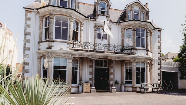 A historic building with a prominent entrance, large windows, and a balcony with ornate ironwork.