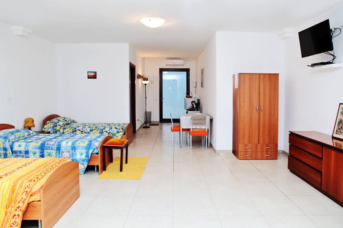 A hotel room with two beds, a desk, a wardrobe, and a television.