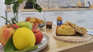 Una encimera de cocina con un plato de frutas, una hogaza de pan y un vaso de jugo.