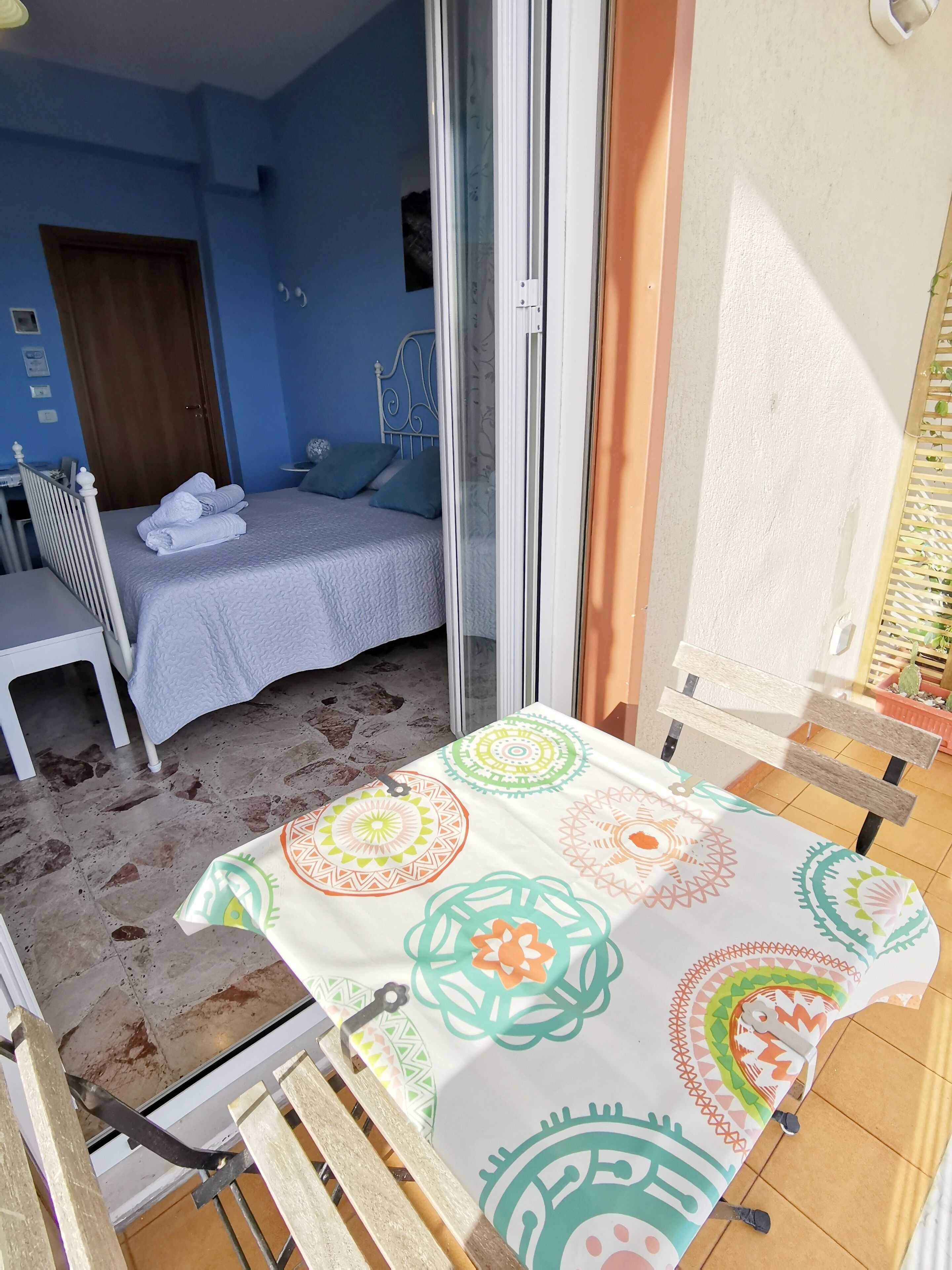 A room with a bed, a desk, and a table with a patterned tablecloth.