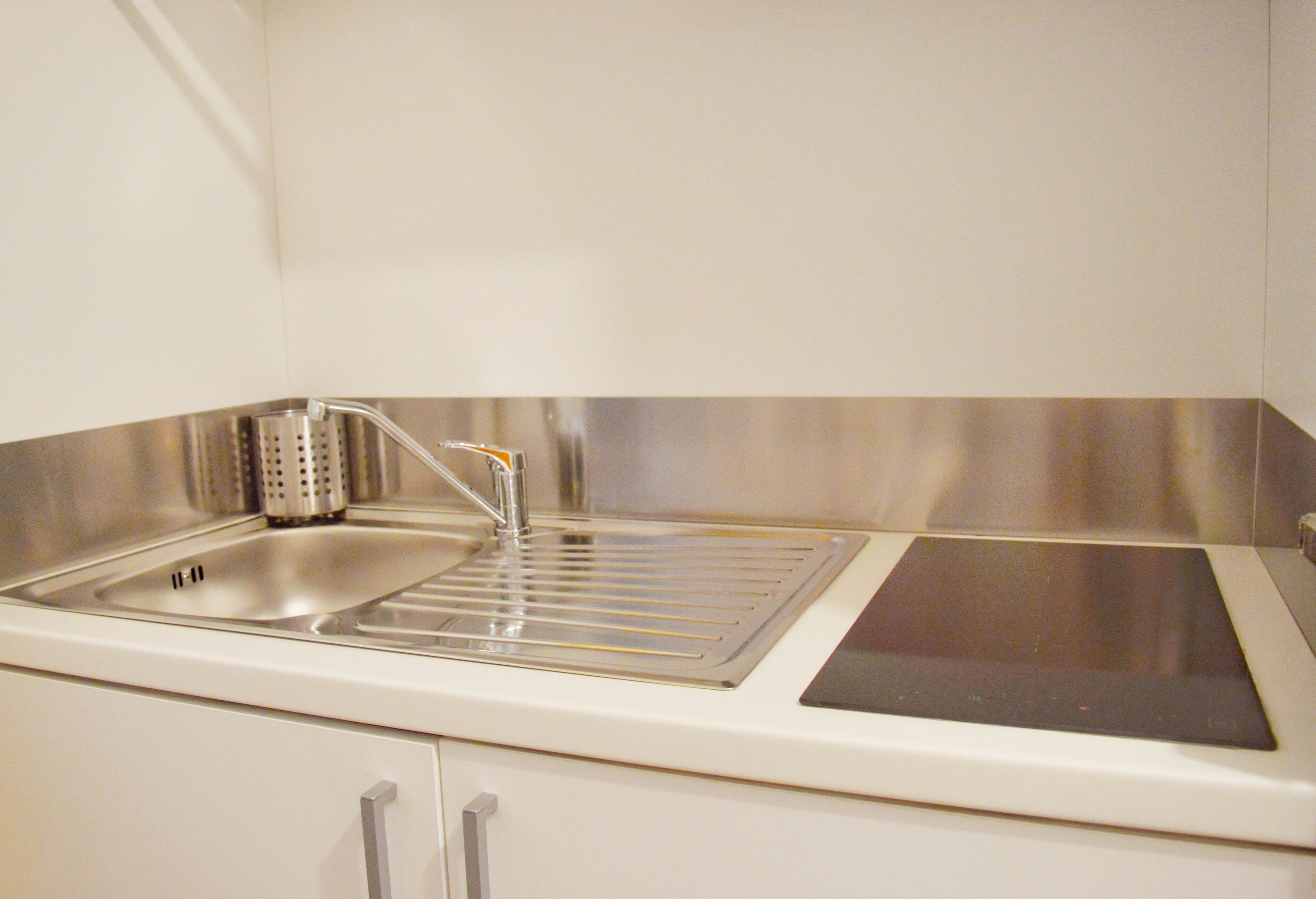 A kitchen with a stainless steel sink, a built-in stove, and white cabinets.