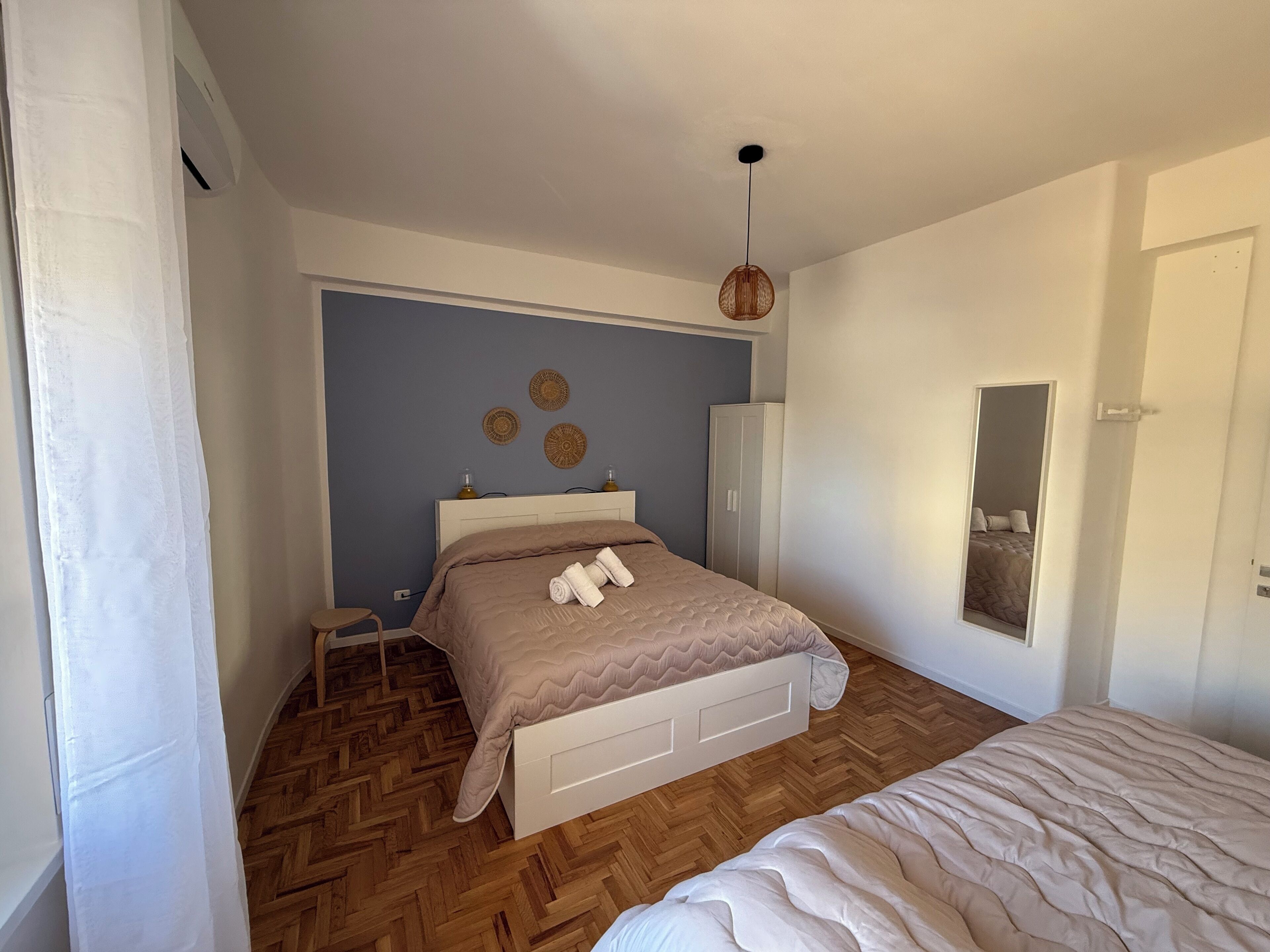 Une chambre à coucher avec un lit, une armoire, un miroir et une petite table.