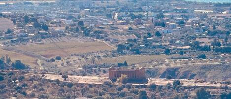 A coastal town with a mix of residential and commercial buildings, a prominent ancient temple, and a view of the sea.