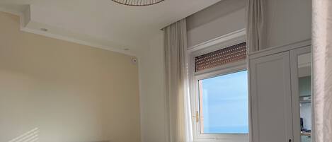 Un dormitorio con cama, ventana, radiador y una silla.