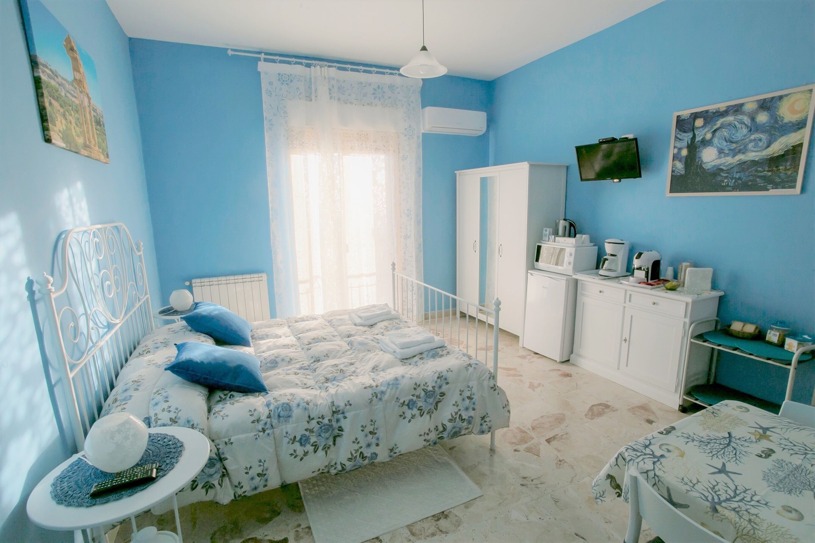 Un dormitorio con cama, mesita de noche, armario, televisor y un cuadro en la pared.