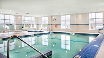 Una piscina techada, sillones reclinables de piscina