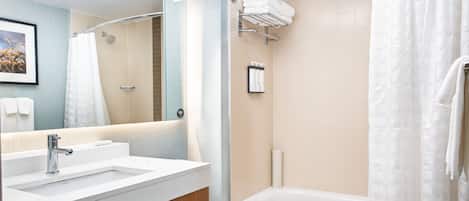 A bathroom with a white sink, mirror, and bathtub.