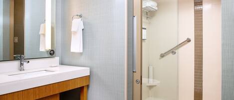 Un baño moderno con tocador, ducha con mampara de vidrio y perchero para toallas.
