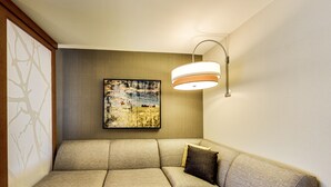 A sectional sofa with a cushion, a wall-mounted lamp, and a framed artwork. - Hyatt Place Edmonton-West (Edmonton)