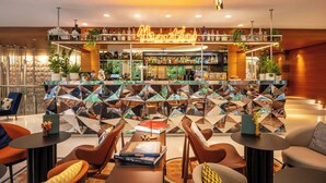 A modern bar area with a neon sign, seating, and a variety of bottles. - Renaissance Paris Republique Hotel (Paris)