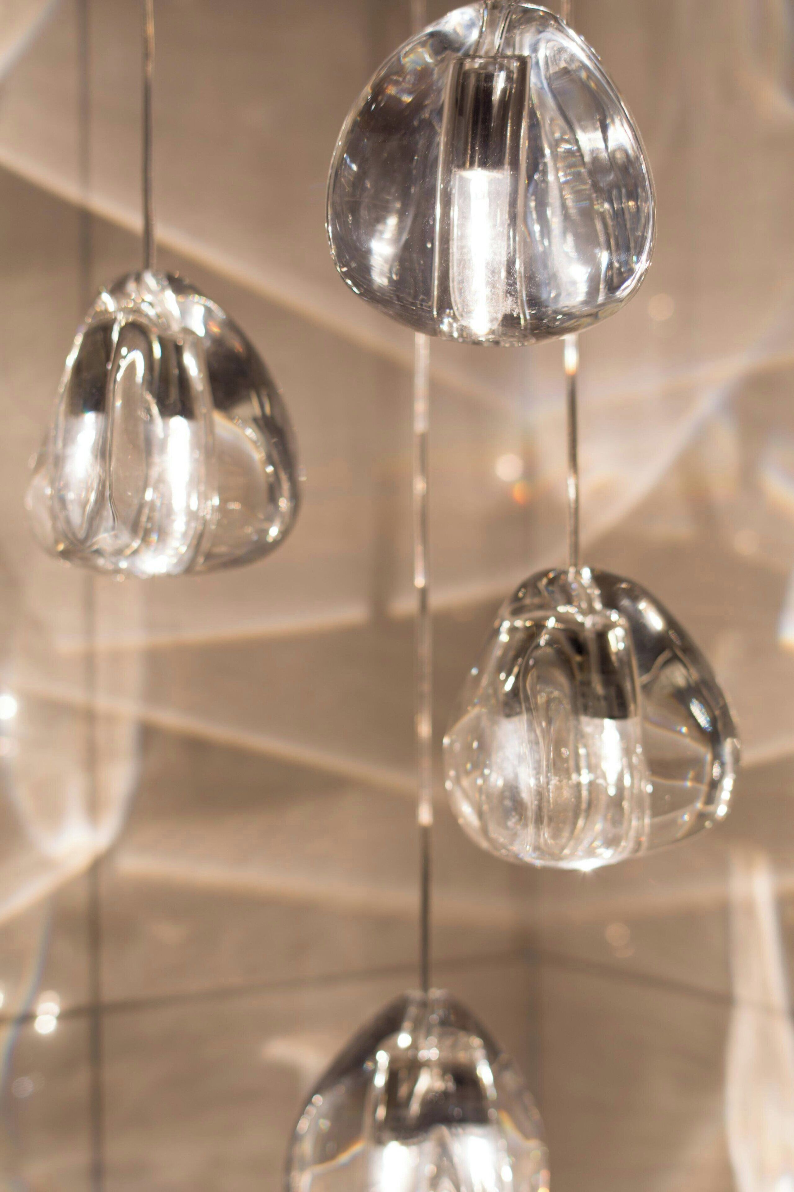 Gros plan de trois luminaires en verre suspendus, dotés d’une surface réfléchissante.