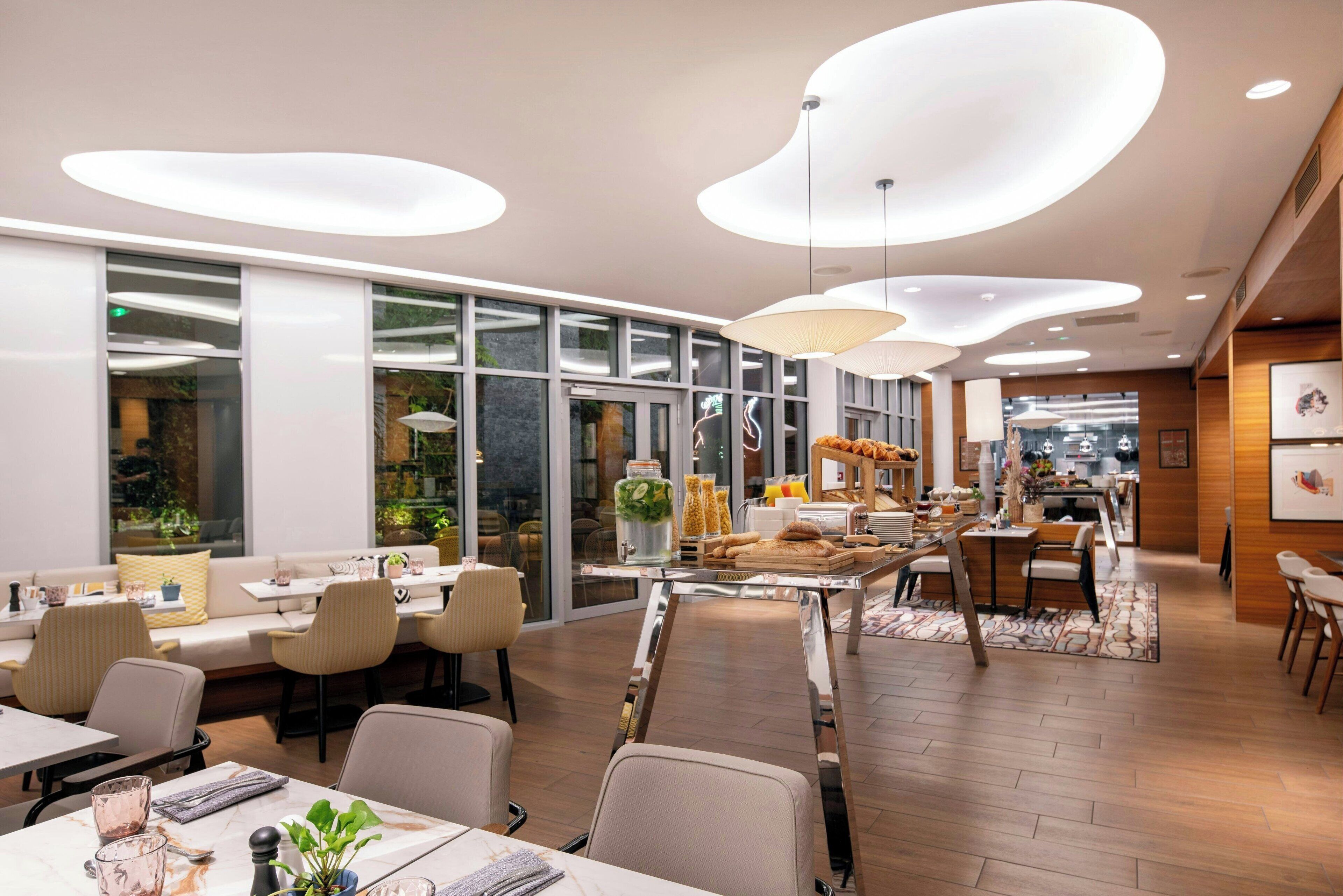 Un comedor moderno con una estación de servicio central, divisiones de vidrio e iluminación contemporánea.