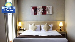 A hotel room with a large bed, two bedside tables with lamps, a telephone, and a wall art piece.