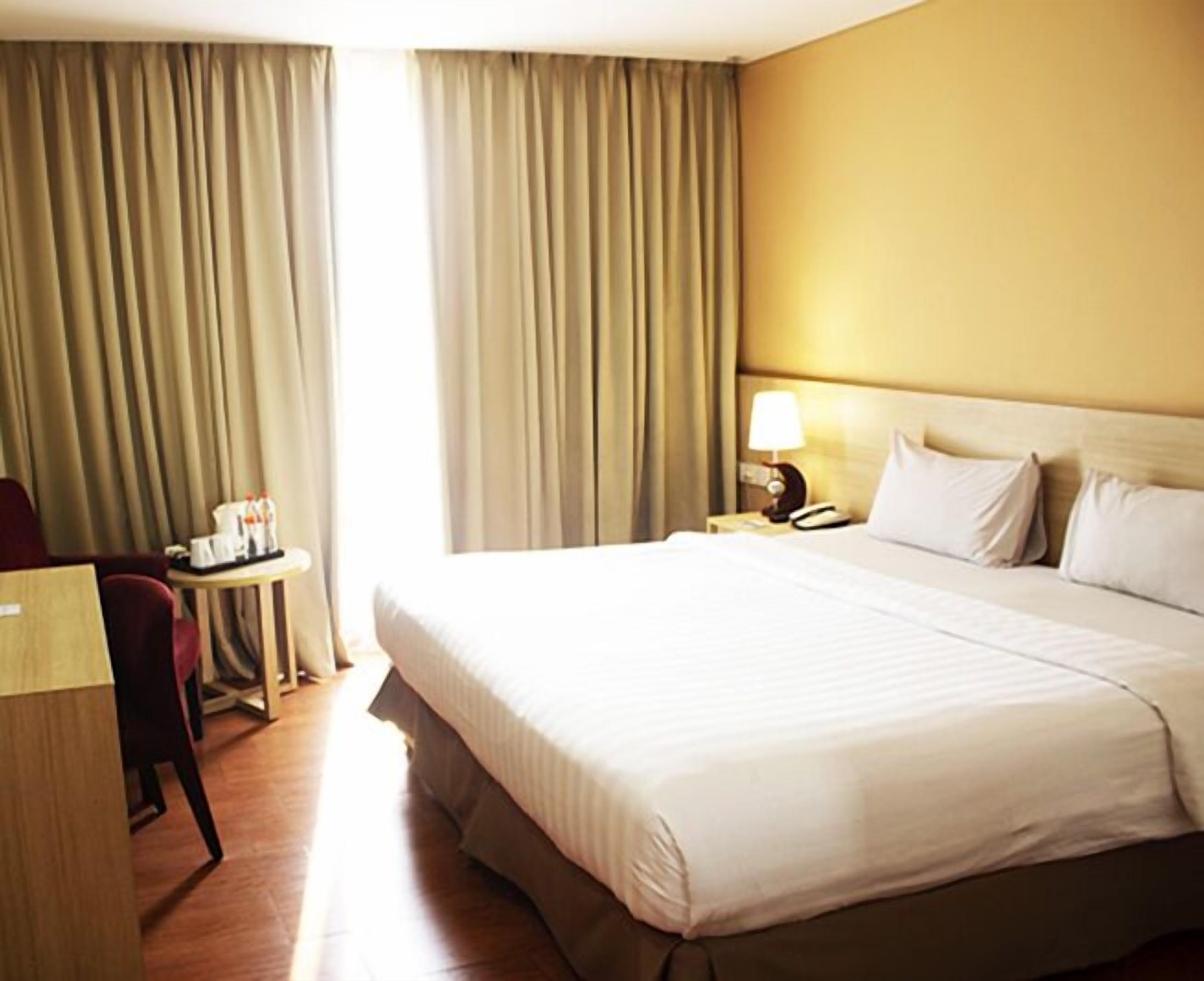 Une chambre d’hôtel avec un grand lit, un bureau et une chaise.