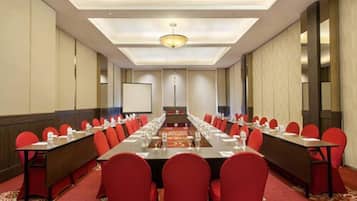 A conference room with a long table, red chairs, and a carpeted floor.