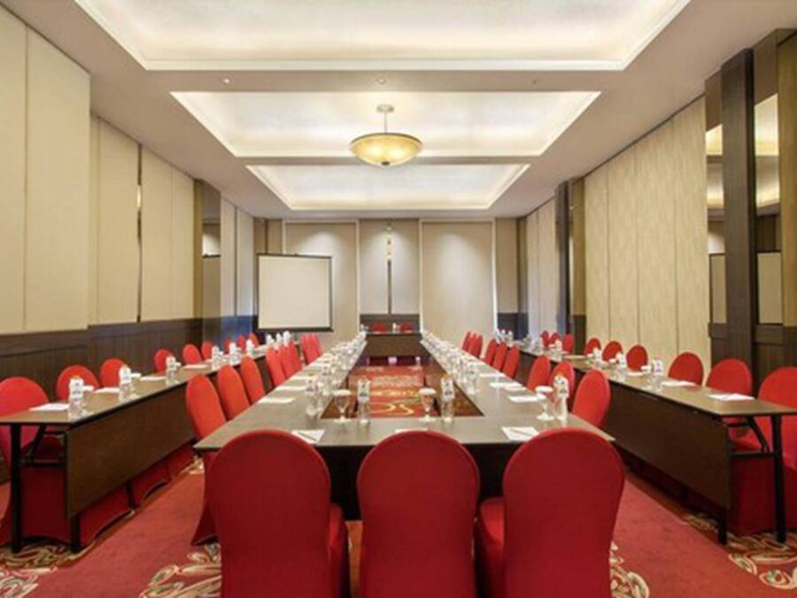 A conference room with a long table, red chairs, and a carpeted floor.