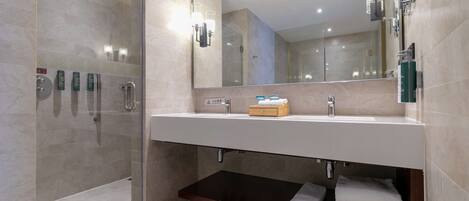 A modern bathroom with a glass shower enclosure, a large mirror, and a vanity with a sink and towel storage.
