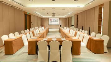 A conference room with a long table, white chairs, and a banner reading "Hilton Garden Inn".