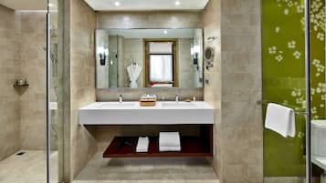 Een moderne badkamer met een douche met glazen wand, een grote spiegel en een wastafelmeubel met een houten plank.