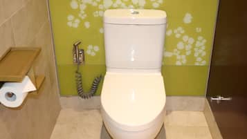 A toilet with a toilet paper holder and a hand dryer.