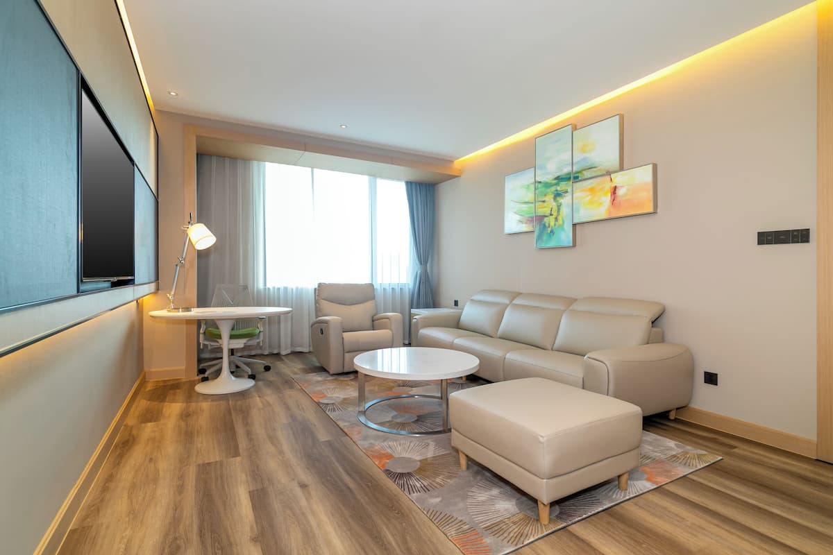 A modern living room with a sofa, armchairs, a coffee table, and a TV.