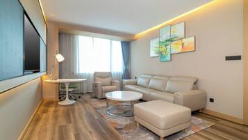 A modern living room with a sofa, armchairs, a coffee table, and a TV.