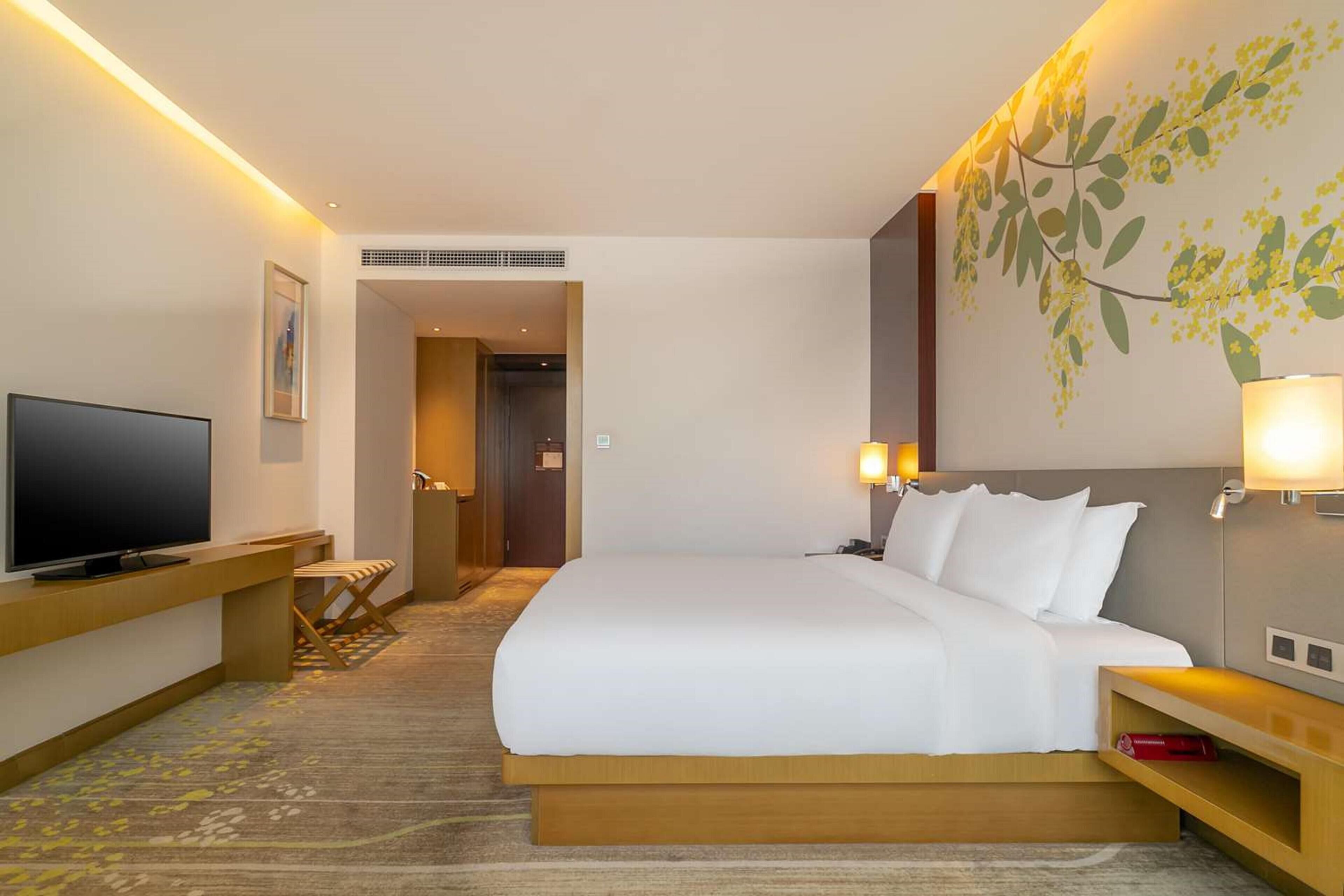 Een hotelkamer met een bed, een televisie, een bureau en een lamp.